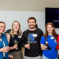 Group of 7 young event attendees standing together and smiling for camera